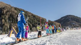 Vals: das Almendorf Skikinder und Lehrer auf Förderbandlift im sonnigen Skigebiet