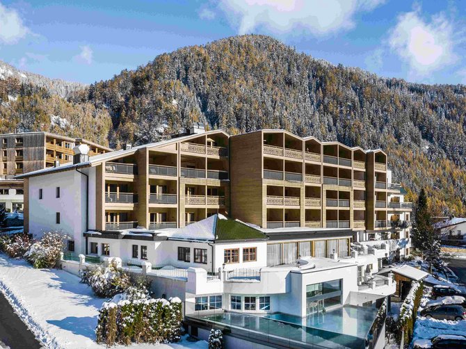 Willkommen in der Ferienregion Gitschberg Jochtal! Modernes Hotel in verschneiter Berglandschaft mit Wald im Hintergrund