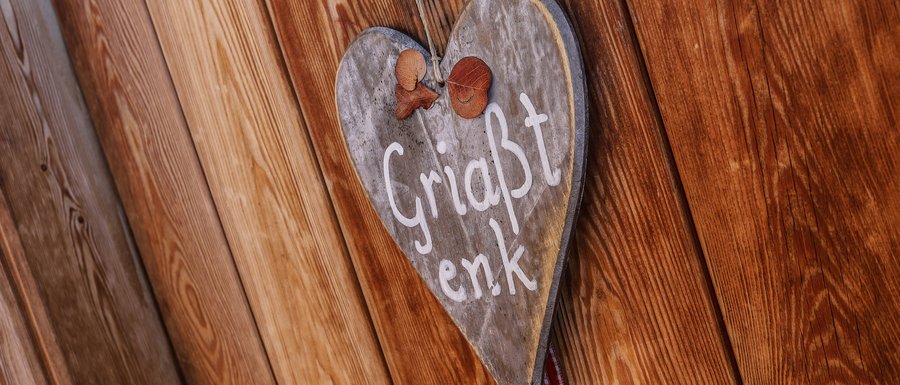 Find your accommodation in South Tyrol A wooden heart with the inscription "Griaßt enk"
