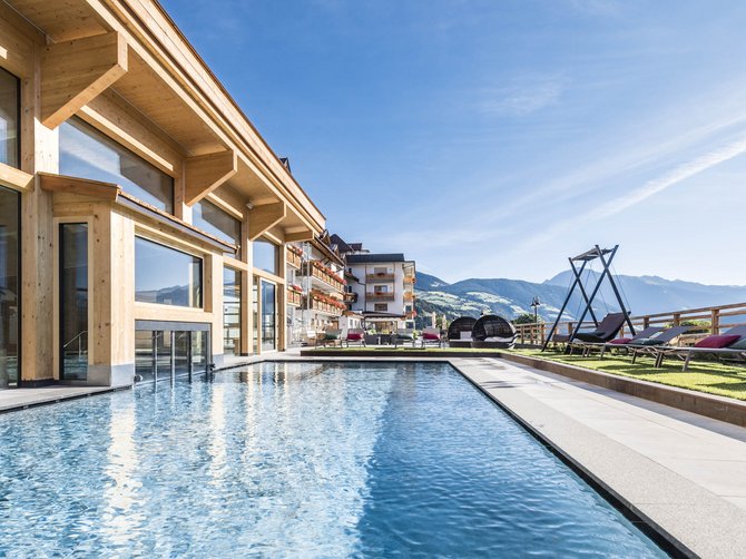Willkommen in der Ferienregion Gitschberg Jochtal! Außenpool neben Hotel mit Bergblick und Liegestühlen