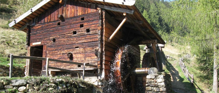 Find your accommodation in South Tyrol Wooden watermill with water wheel in forested mountain area