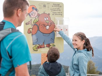 Das Altfasstal bei Meransen Familie liest Info-Tafel für Räuberjagd am Gitschberg im Freien