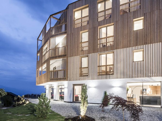 Willkommen in der Ferienregion Gitschberg Jochtal! Modernes Holzhaus mit großen Fenstern bei Dämmerung