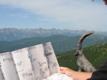 Das Bergdorf Meransen Person hält Karte mit Bergblick und Holzskulptur einer Ziege