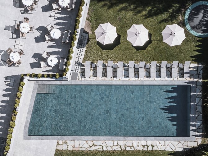 Willkommen in der Ferienregion Gitschberg Jochtal! Drohnenaufnahme eines Pools mit Sonnenliegen, Sonnenschirmen und Sitzbereich