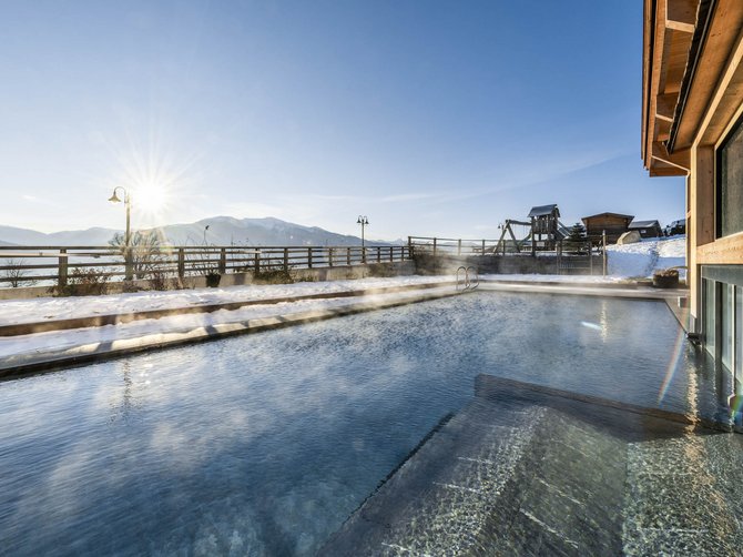 Willkommen in der Ferienregion Gitschberg Jochtal! Beheizter Außenpool mit Mountainblick und Schnee im Sonnenschein