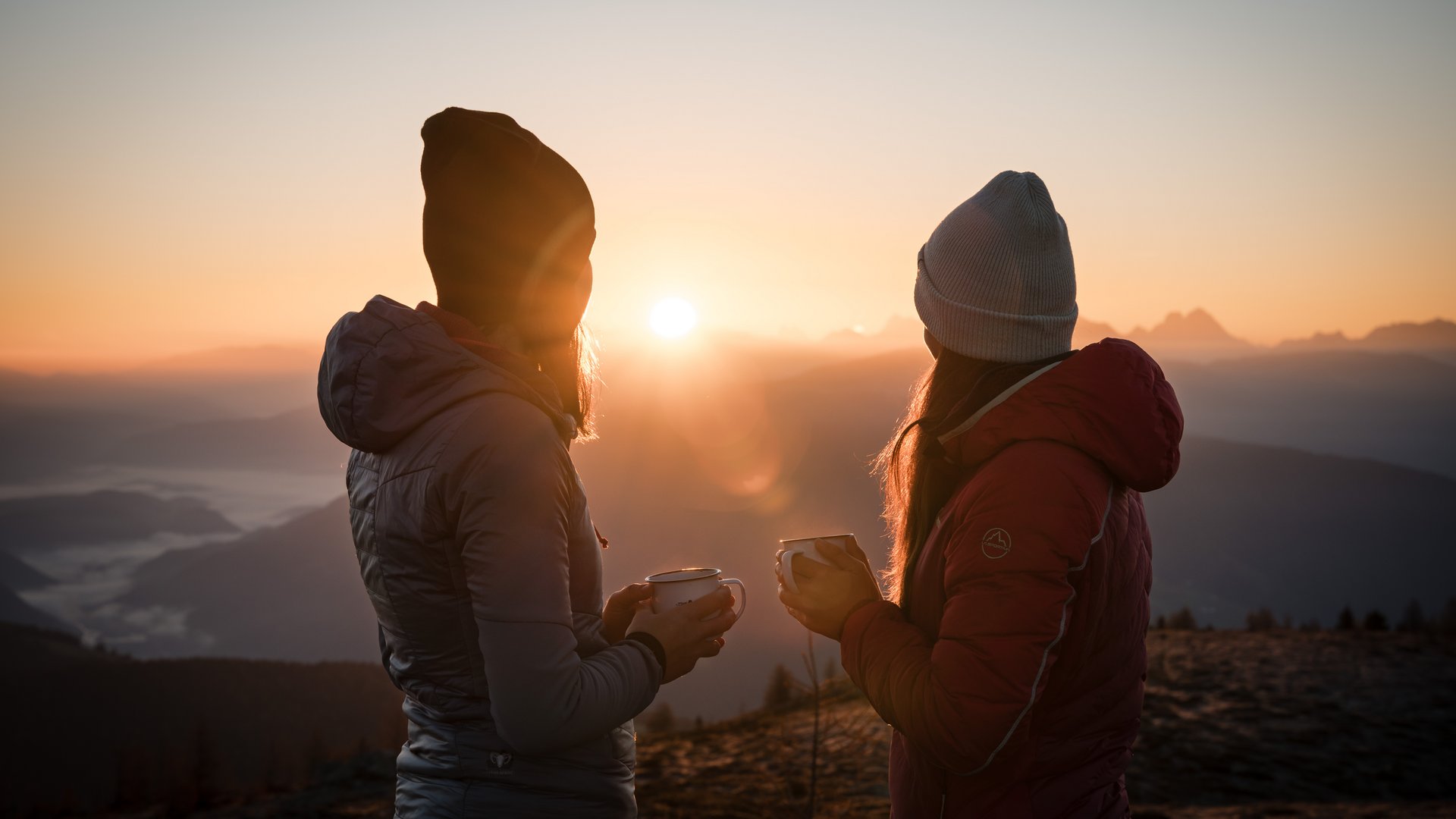 De Almencard: de plus in vakantiegenoegen Twee vrouwen die bij zonsopgang hete thee drinken in de bergen