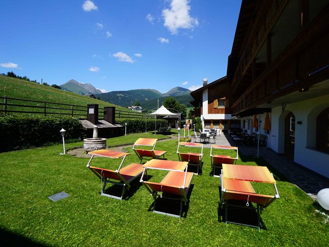 Willkommen in der Ferienregion Gitschberg Jochtal! Garten mit Liegestühlen vor einem Alpenhotel bei sonnigem Wetter