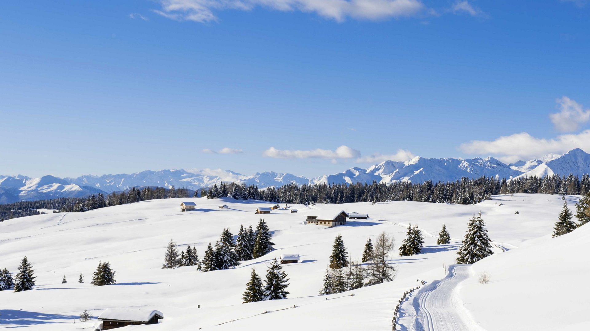 De Rodenecker-Lüsner Alm Sneeuwbedekte bergen met huizen en bomen onder een blauwe lucht