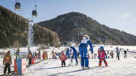 Vals: das Almendorf Kinder lernen Skifahren auf einem verschneiten Anfängerhang mit Skilehrern