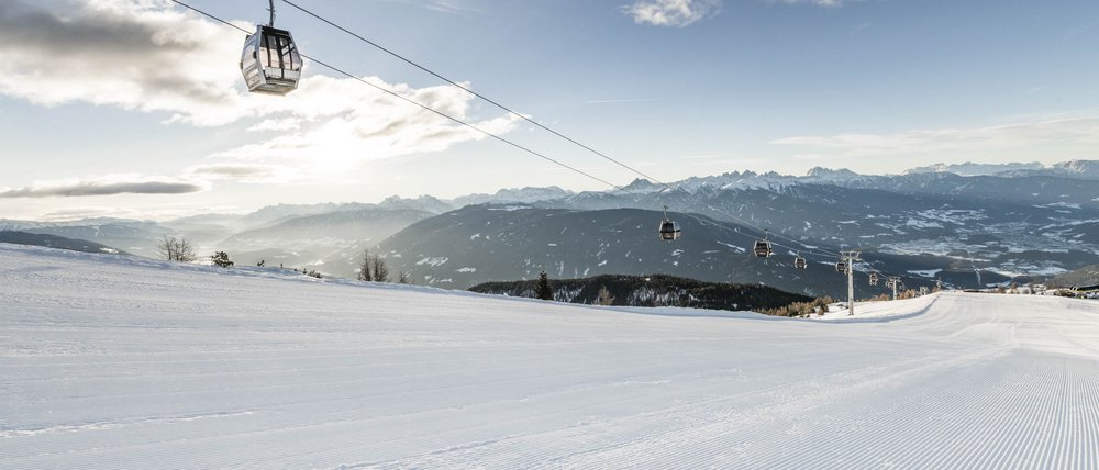 Find your accommodation in South Tyrol Empty ski slope with gondola lift and mountains in the background