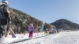 Vals: das Almendorf Kinder lernen Skifahren auf einem Förderband in einem Skigebiet mit Bergen