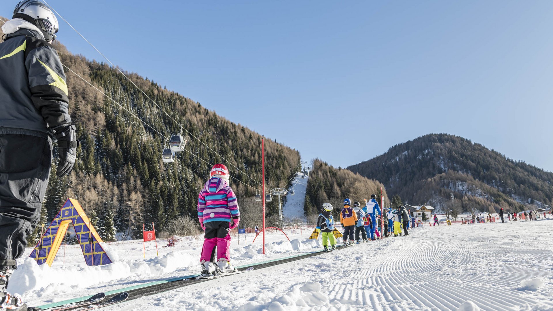 Vals: das Almendorf Kinder lernen Skifahren auf einem Förderband in einem Skigebiet mit Bergen