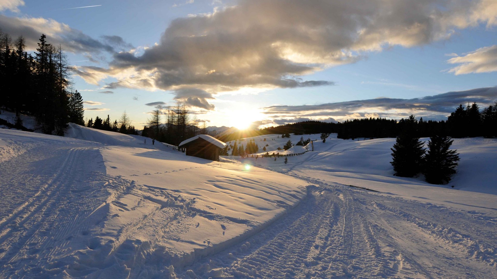De Rodenecker-Lüsner Alm Besneeuwd landschap met cabine en zonsondergang achter bomen