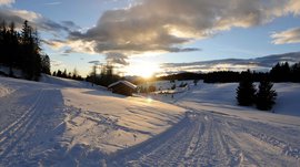 De Rodenecker-Lüsner Alm Besneeuwd landschap met cabine en zonsondergang achter bomen