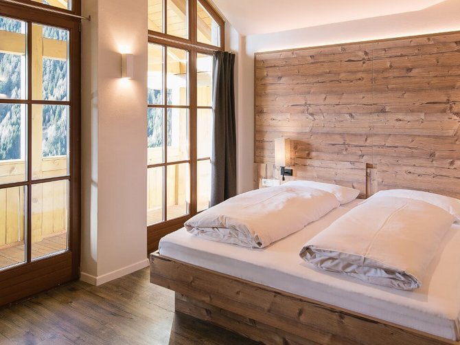 Willkommen in der Ferienregion Gitschberg Jochtal! Modernes Schlafzimmer mit Holzdesign und großem Fenster mit Bergblick