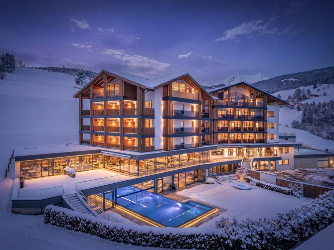 Willkommen in der Ferienregion Gitschberg Jochtal! Beleuchtetes Hotel mit Außenpool in verschneiter Berglandschaft bei Nacht